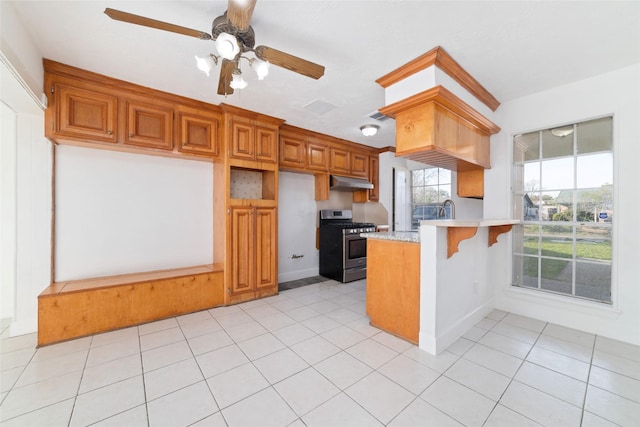kitchen featuring stainless steel gas range oven, under cabinet range hood, a peninsula, light countertops, and ceiling fan