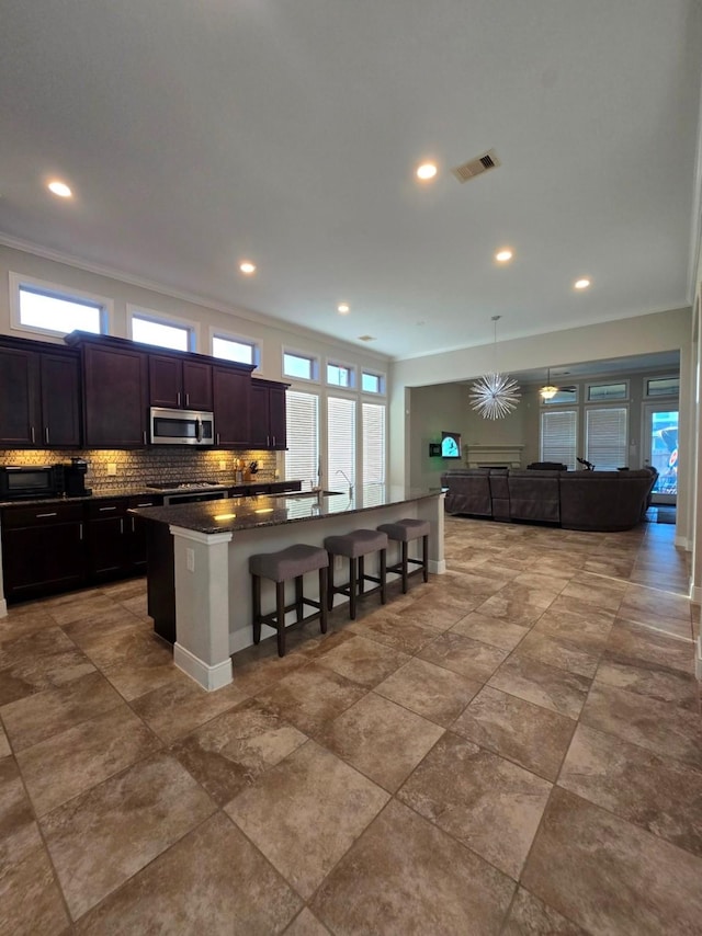 3207 Karleigh Way, Richmond, TX 77406 - kitchen with stainless steel microwave, a breakfast bar, backsplash, an island with sink, and recessed lighting