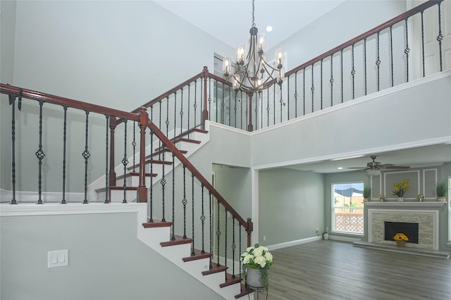 15202 Delbarton Dr, Houston, TX 77083 - staircase with wood finished floors, a chandelier, a fireplace with raised hearth, a towering ceiling, and a ceiling fan