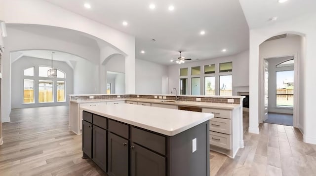 kitchen with a large island, a sink, a ceiling fan, light countertops, and recessed lighting