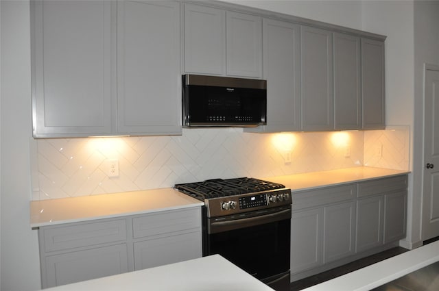673 Royal Arch Dr, Conroe, TX 77304 - kitchen featuring gas stove, gray cabinetry, light countertops, and backsplash