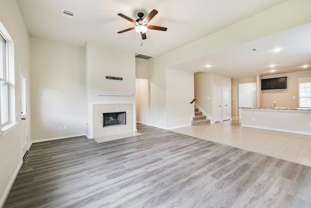 12638 Silver Winter Trl, Houston, TX 77014 - unfurnished living room featuring stairway, ceiling fan, a tile fireplace, recessed lighting, and light wood-style flooring