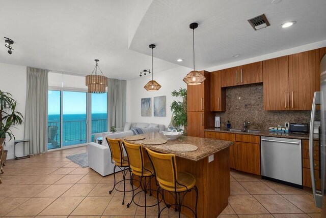310 Padre Blvd Unit 2305, South Padre Island, TX 78597 - kitchen with dishwasher, brown cabinetry, backsplash, light tile patterned floors, and a kitchen island