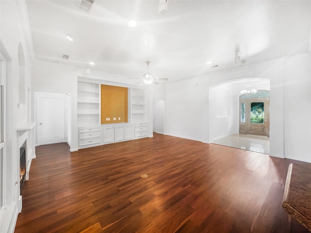 2424 Katy Hockley Cut Off Rd, Katy, TX 77493 - unfurnished living room featuring arched walkways, wood finished floors, crown molding, built in shelves, and a ceiling fan