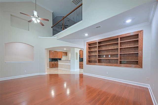2409 Spears Dr, Humble, TX 77396 - unfurnished living room with arched walkways, ceiling fan, baseboards, a high ceiling, and ornamental molding