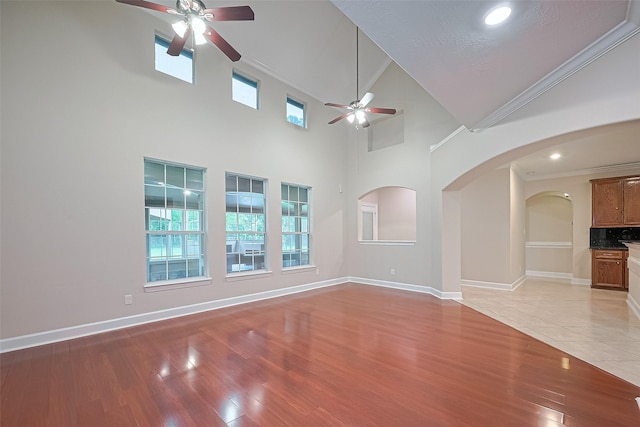 2409 Spears Dr, Humble, TX 77396 - unfurnished living room with a ceiling fan, light wood-type flooring, arched walkways, ornamental molding, and baseboards