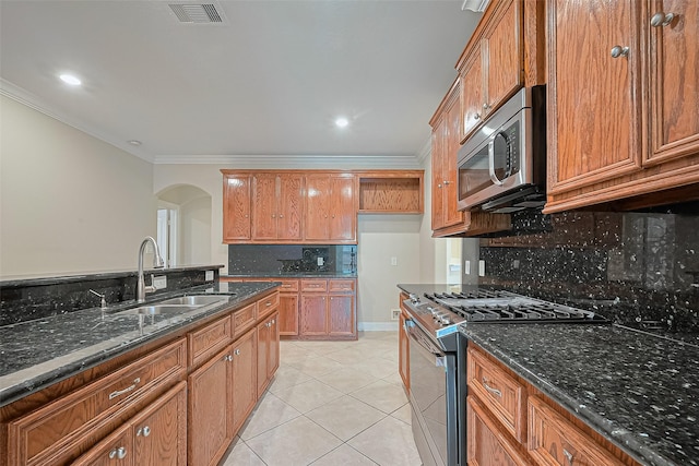 2409 Spears Dr, Humble, TX 77396 - kitchen featuring stainless steel appliances, a sink, arched walkways, ornamental molding, and brown cabinets