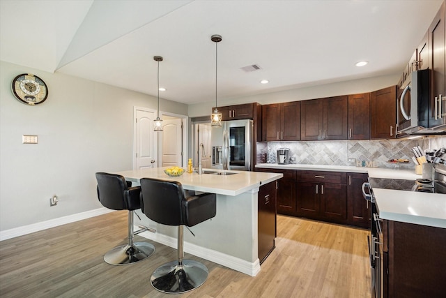 1623 25th St, Dickinson, TX 77539 - kitchen with appliances with stainless steel finishes, light countertops, a kitchen breakfast bar, light wood-style flooring, and recessed lighting