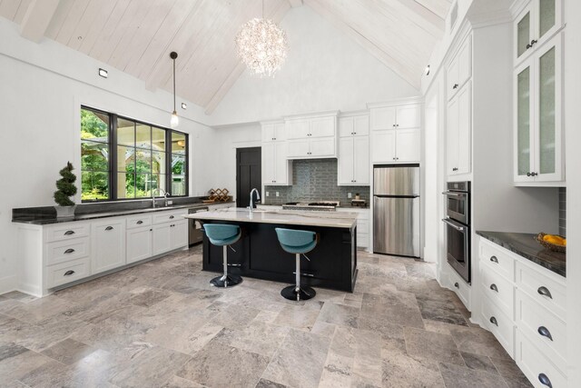 129 Stagecoach Cir, Huntsville, TX 77340 - kitchen featuring stainless steel appliances, a kitchen bar, white cabinets, decorative backsplash, and hanging light fixtures