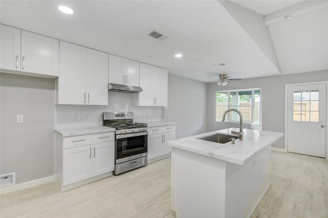 4614 Wee Lassie Ln, Houston, TX 77084 - kitchen with gas stove, under cabinet range hood, a sink, a ceiling fan, and light stone counters