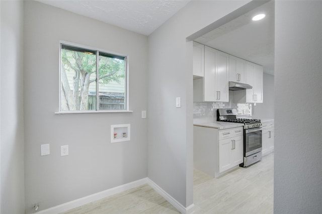 4614 Wee Lassie Ln, Houston, TX 77084 - kitchen featuring gas range, under cabinet range hood, light countertops, white cabinets, and backsplash