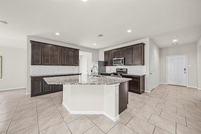 29618 Juntti Park Ct, Katy, TX 77494 - kitchen featuring appliances with stainless steel finishes, backsplash, a sink, light tile patterned floors, and dark brown cabinets