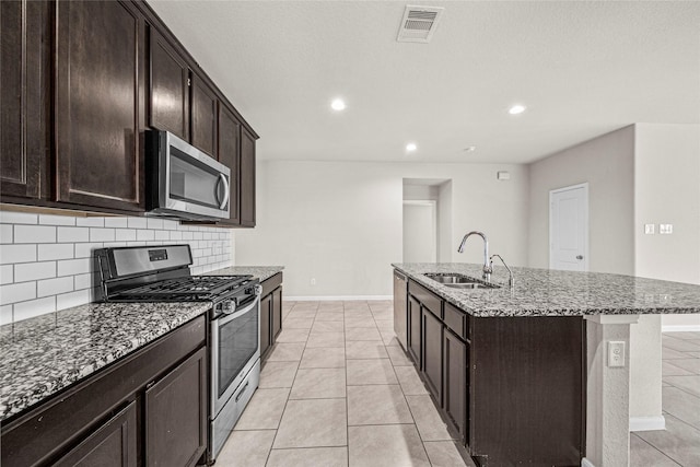 29618 Juntti Park Ct, Katy, TX 77494 - kitchen with appliances with stainless steel finishes, a sink, dark stone counters, a kitchen island with sink, and decorative backsplash