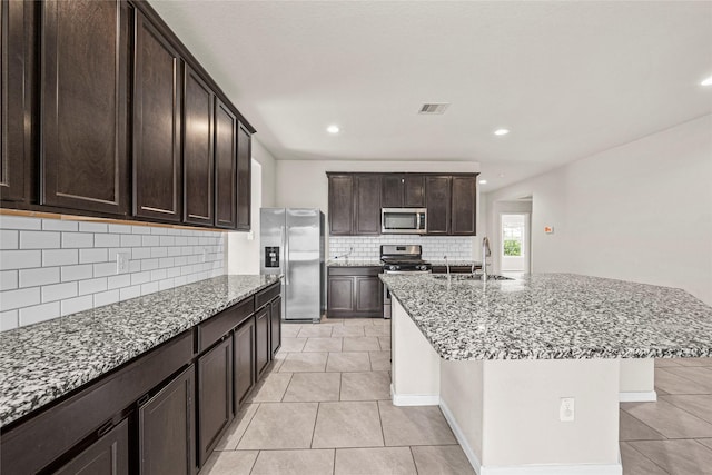 29618 Juntti Park Ct, Katy, TX 77494 - kitchen with stainless steel appliances, a sink, decorative backsplash, light stone counters, and light tile patterned floors