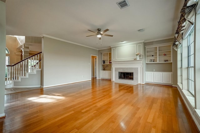 4415 April Meadow Way, Sugar Land, TX 77479 - unfurnished living room featuring ceiling fan, light wood-type flooring, crown molding, a tiled fireplace, and baseboards