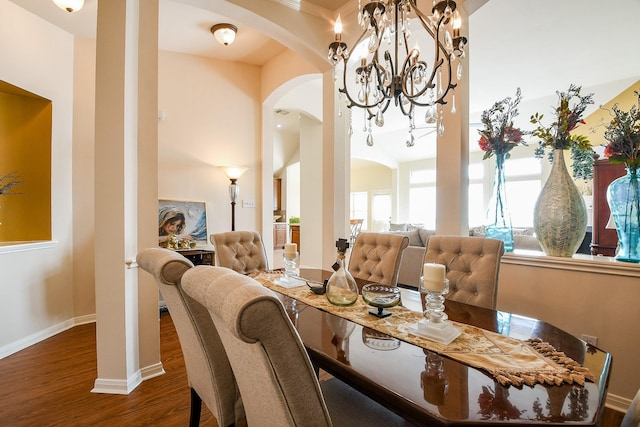 16211 Fleethaven Ln, Houston, TX 77084 - dining room featuring arched walkways, dark wood-style floors, a chandelier, baseboards, and ornate columns