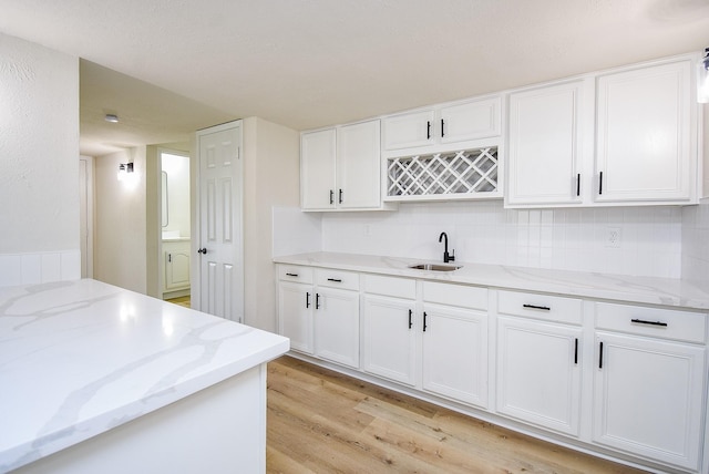 7227 La Granada Dr, Houston, TX 77083 - kitchen featuring a sink, light wood-style flooring, backsplash, and white cabinets