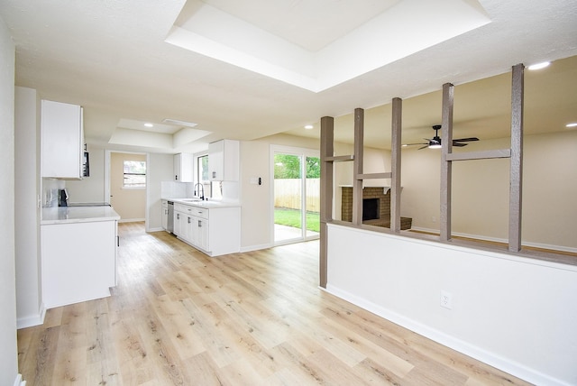 7227 La Granada Dr, Houston, TX 77083 - unfurnished living room featuring ceiling fan, a tray ceiling, light wood-type flooring, a fireplace, and recessed lighting
