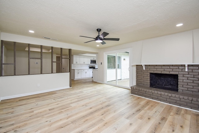 7227 La Granada Dr, Houston, TX 77083 - unfurnished living room featuring light wood-style flooring, ceiling fan, a textured ceiling, a fireplace, and recessed lighting