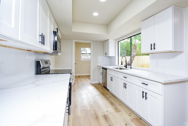 7227 La Granada Dr, Houston, TX 77083 - kitchen featuring a sink, stainless steel appliances, light wood-type flooring, white cabinetry, and recessed lighting