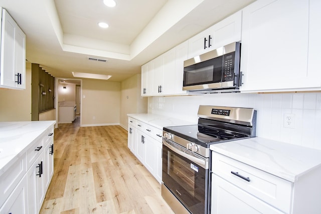 7227 La Granada Dr, Houston, TX 77083 - kitchen with stainless steel appliances, light wood-style flooring, decorative backsplash, white cabinets, and recessed lighting