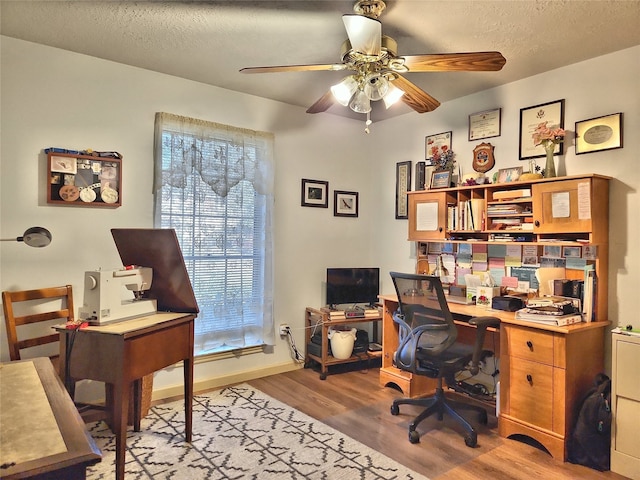 home office featuring a ceiling fan, light wood-style flooring, baseboards, and a textured ceiling