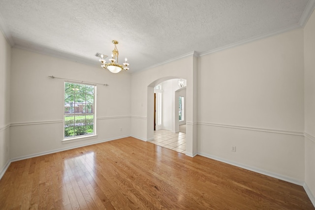 12690 Longmire Way, Conroe, TX 77304 - spare room featuring arched walkways, hardwood / wood-style floors, a chandelier, a textured ceiling, and ornamental molding