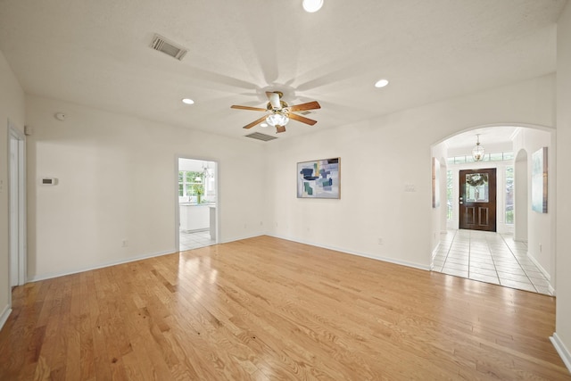 12690 Longmire Way, Conroe, TX 77304 - unfurnished living room featuring arched walkways, light wood-style floors, a ceiling fan, recessed lighting, and baseboards