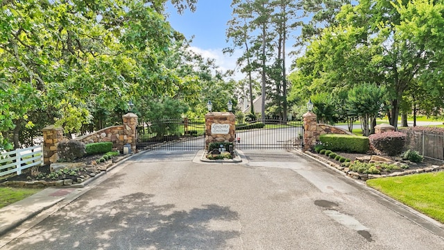 12690 Longmire Way, Conroe, TX 77304 - view of asphalt street with curbs, a gate, street lighting, a gated entry, and view of wooded area