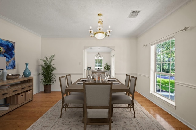 12690 Longmire Way, Conroe, TX 77304 - dining room with a chandelier, arched walkways, crown molding, light wood-style floors, and a textured ceiling