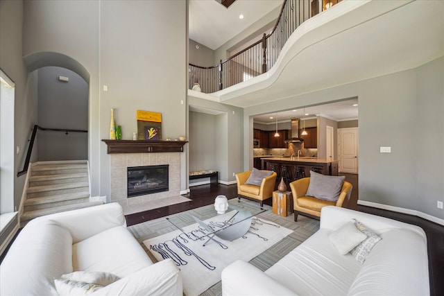 2918 Auburn Path, Sugar Land, TX 77479 - living room featuring a towering ceiling, baseboards, stairs, a tiled fireplace, and arched walkways