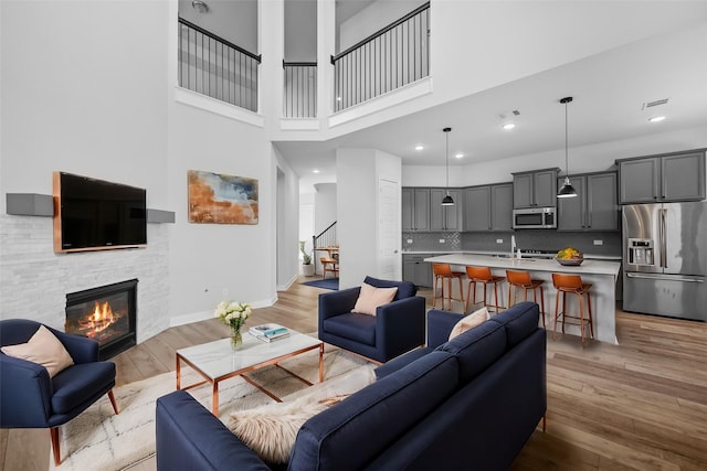 4325 Victoria Pine Dr, Spring, TX 77386 - living area with light wood-style floors, stairway, a high ceiling, baseboards, and a stone fireplace
