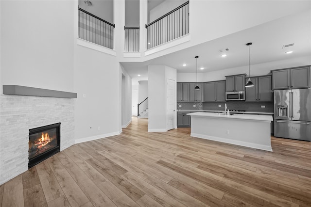 4325 Victoria Pine Dr, Spring, TX 77386 - kitchen featuring appliances with stainless steel finishes, light countertops, gray cabinets, open floor plan, and light wood-style flooring
