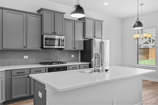 4325 Victoria Pine Dr, Spring, TX 77386 - kitchen featuring appliances with stainless steel finishes, gray cabinets, a sink, backsplash, and light wood-type flooring