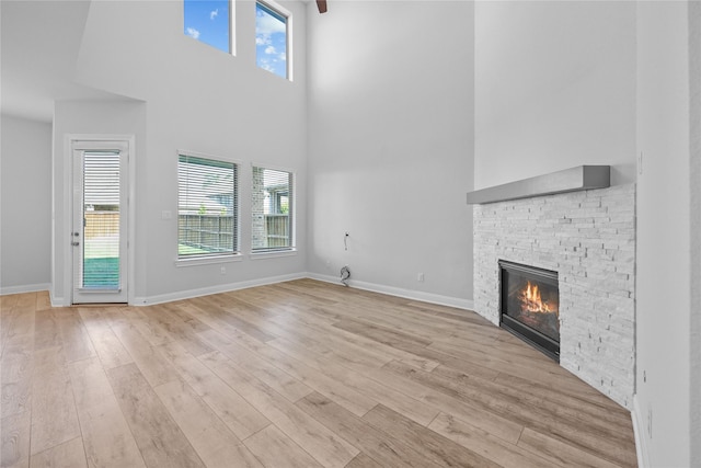 4325 Victoria Pine Dr, Spring, TX 77386 - unfurnished living room featuring a high ceiling, a fireplace, light wood finished floors, and healthy amount of natural light
