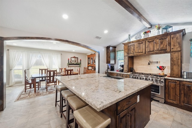 96 Fm 2550th Rd, Huntsville, TX 77320 - kitchen with high end range, a sink, light stone countertops, arched walkways, and a breakfast bar