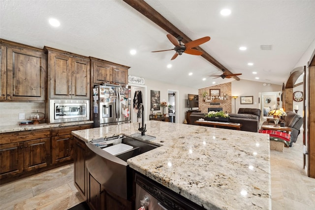 96 Fm 2550th Rd, Huntsville, TX 77320 - kitchen with stainless steel appliances, a ceiling fan, a brick fireplace, a sink, and light stone countertops
