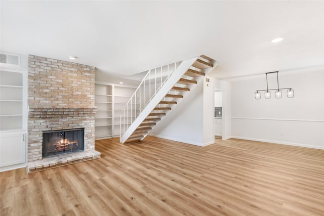 5524 Beverlyhill St Unit 4, Houston, TX 77056 - unfurnished living room featuring wood finished floors, a brick fireplace, stairway, baseboards, and recessed lighting