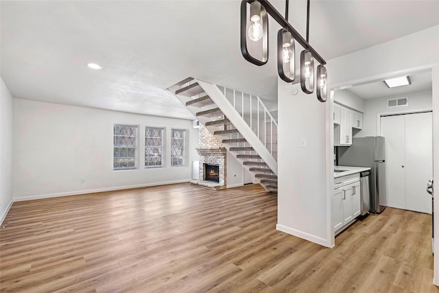 5524 Beverlyhill St Unit 4, Houston, TX 77056 - unfurnished living room featuring baseboards, light wood finished floors, stairs, recessed lighting, and a brick fireplace