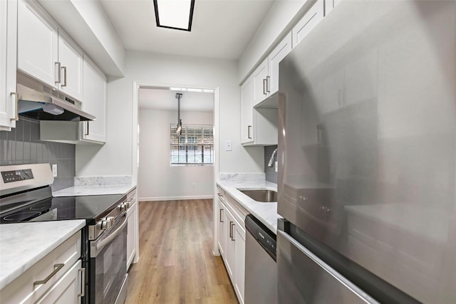 5524 Beverlyhill St Unit 4, Houston, TX 77056 - kitchen featuring stainless steel appliances, under cabinet range hood, light wood-style flooring, and white cabinetry