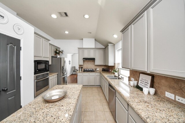 15122 Heron Meadow Ln, Cypress, TX 77429 - kitchen featuring stainless steel appliances, a sink, lofted ceiling, tasteful backsplash, and light stone counters