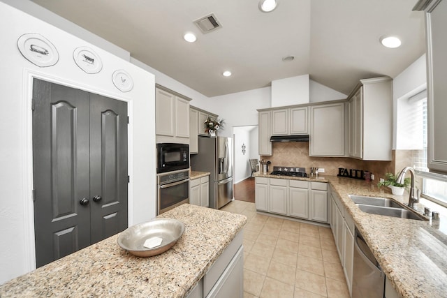 15122 Heron Meadow Ln, Cypress, TX 77429 - kitchen with stainless steel appliances, a sink, under cabinet range hood, tasteful backsplash, and light tile patterned floors
