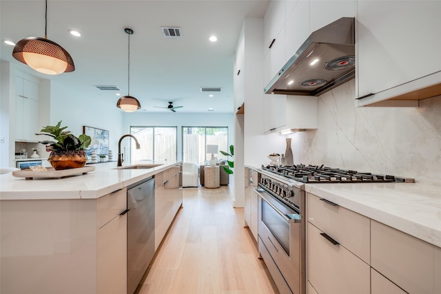 1209 W Bell St, Houston, TX 77019 - kitchen featuring range hood, stainless steel appliances, a sink, light wood finished floors, and backsplash