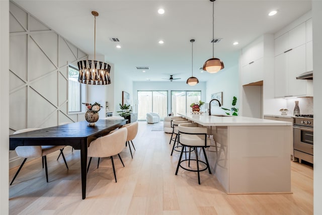 1209 W Bell St, Houston, TX 77019 - kitchen featuring stainless steel stove, modern cabinets, light wood-style floors, light countertops, and white cabinets