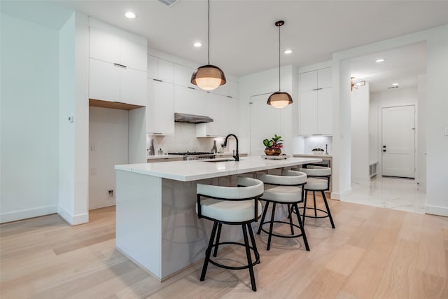 1209 W Bell St, Houston, TX 77019 - kitchen featuring a sink, a breakfast bar area, light wood-style flooring, modern cabinets, and white cabinets