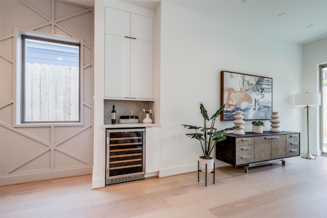 1209 W Bell St, Houston, TX 77019 - indoor dry bar with beverage cooler, light wood finished floors, decorative backsplash, and baseboards