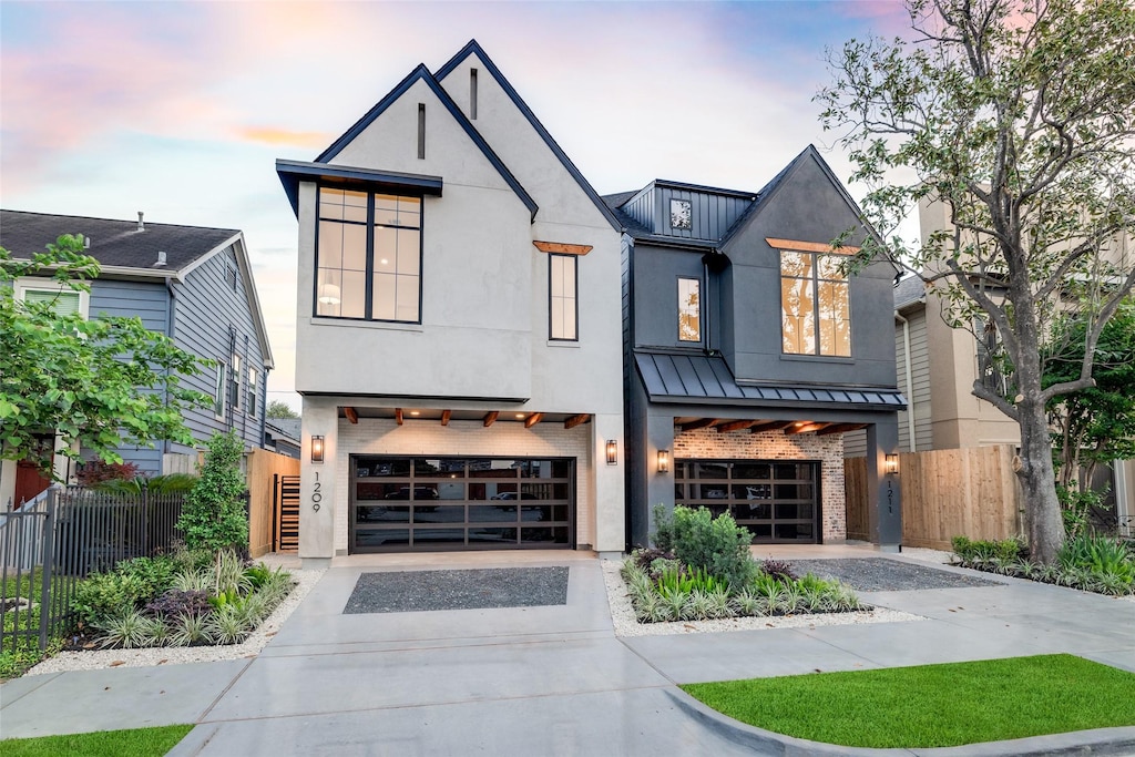 1209 W Bell St, Houston, TX 77019 - view of front of home with a standing seam roof, driveway, an attached garage, and brick siding