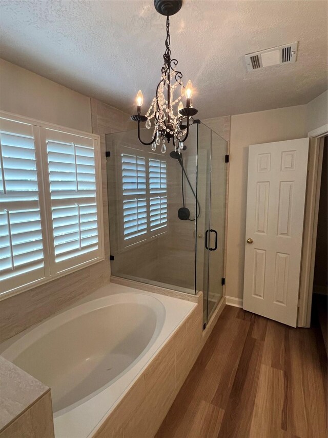 4326 Holly Terrace Ct, Pasadena, TX 77505 - bathroom with a chandelier, a shower stall, a textured ceiling, wood finished floors, and a bath