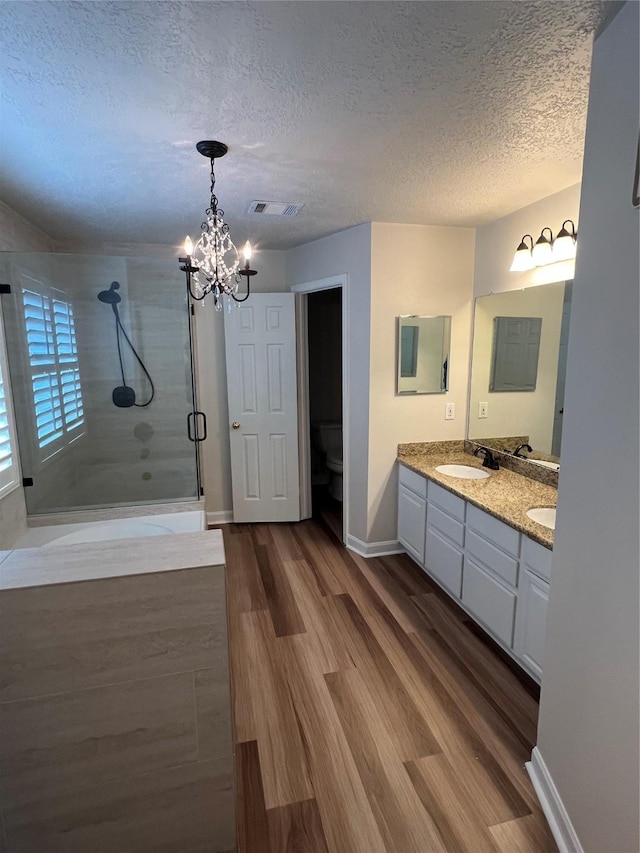 4326 Holly Terrace Ct, Pasadena, TX 77505 - full bath with a shower stall, a chandelier, a textured ceiling, double vanity, and wood finished floors