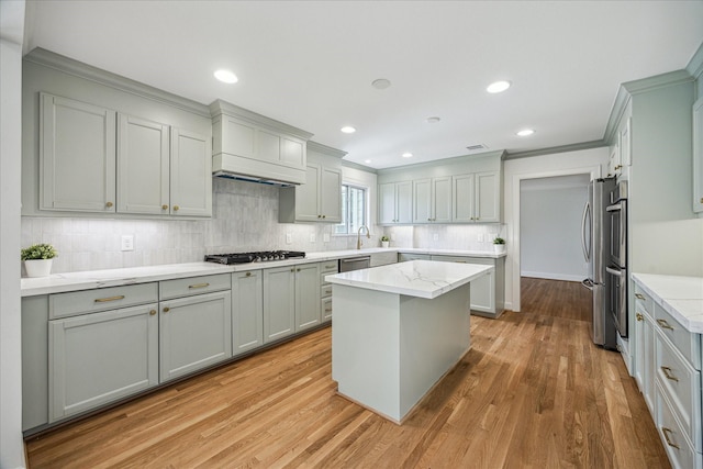 2518 Glen Haven Blvd, Houston, TX 77030 - kitchen featuring appliances with stainless steel finishes, ornamental molding, light wood-style floors, tasteful backsplash, and a center island